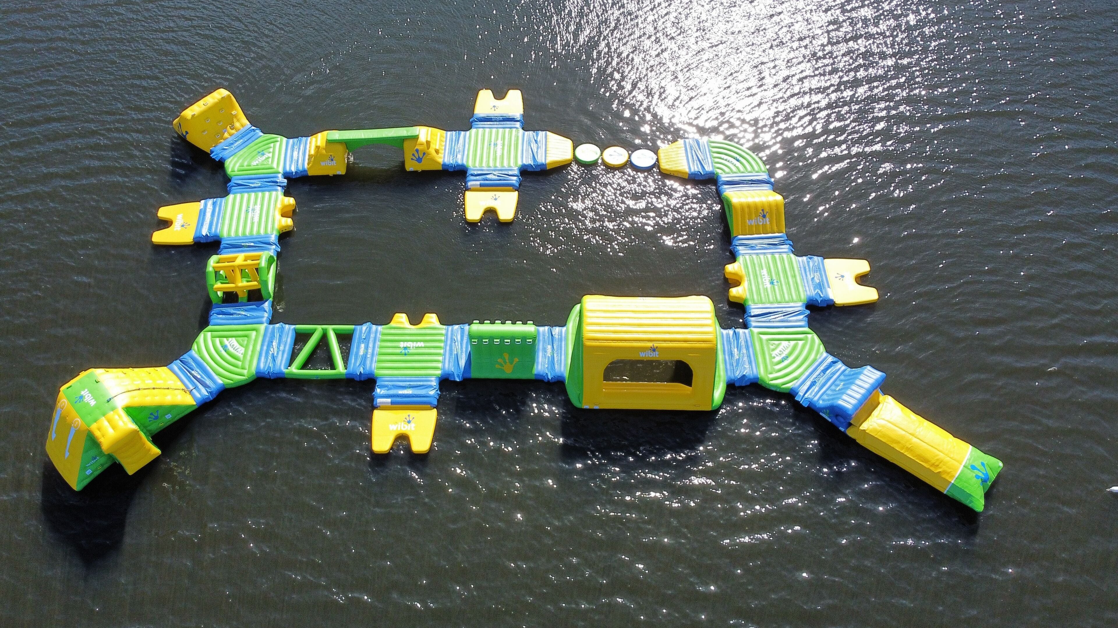 Une structure flottante composée de blocs en plastique emboîtés les uns dans les autres, de couleurs jaune, verte et bleue, et qui flotte sur l’eau.