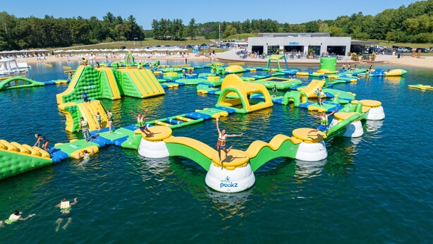 Een openluchts waterpark met verschillende opblaasbare speelstructuren en een gebouw op de achtergrond.