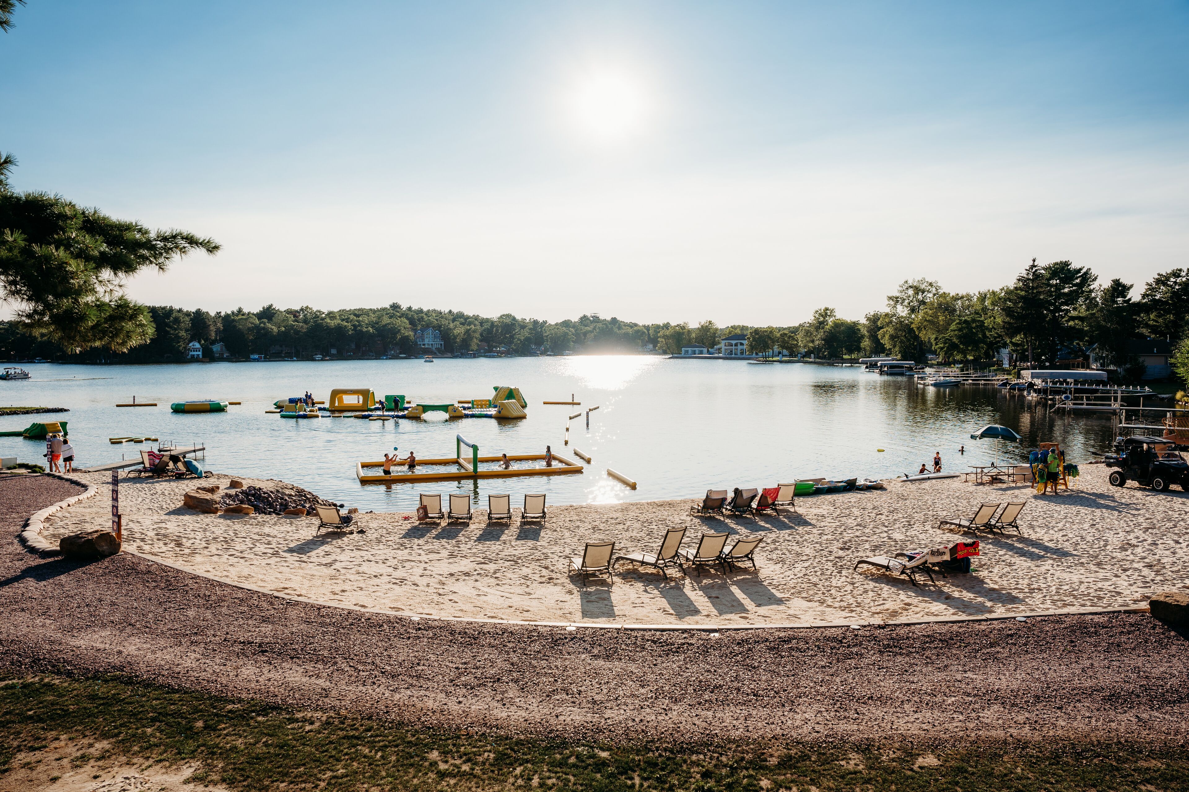 A beach with sun loungers and a dock extending into calm water.