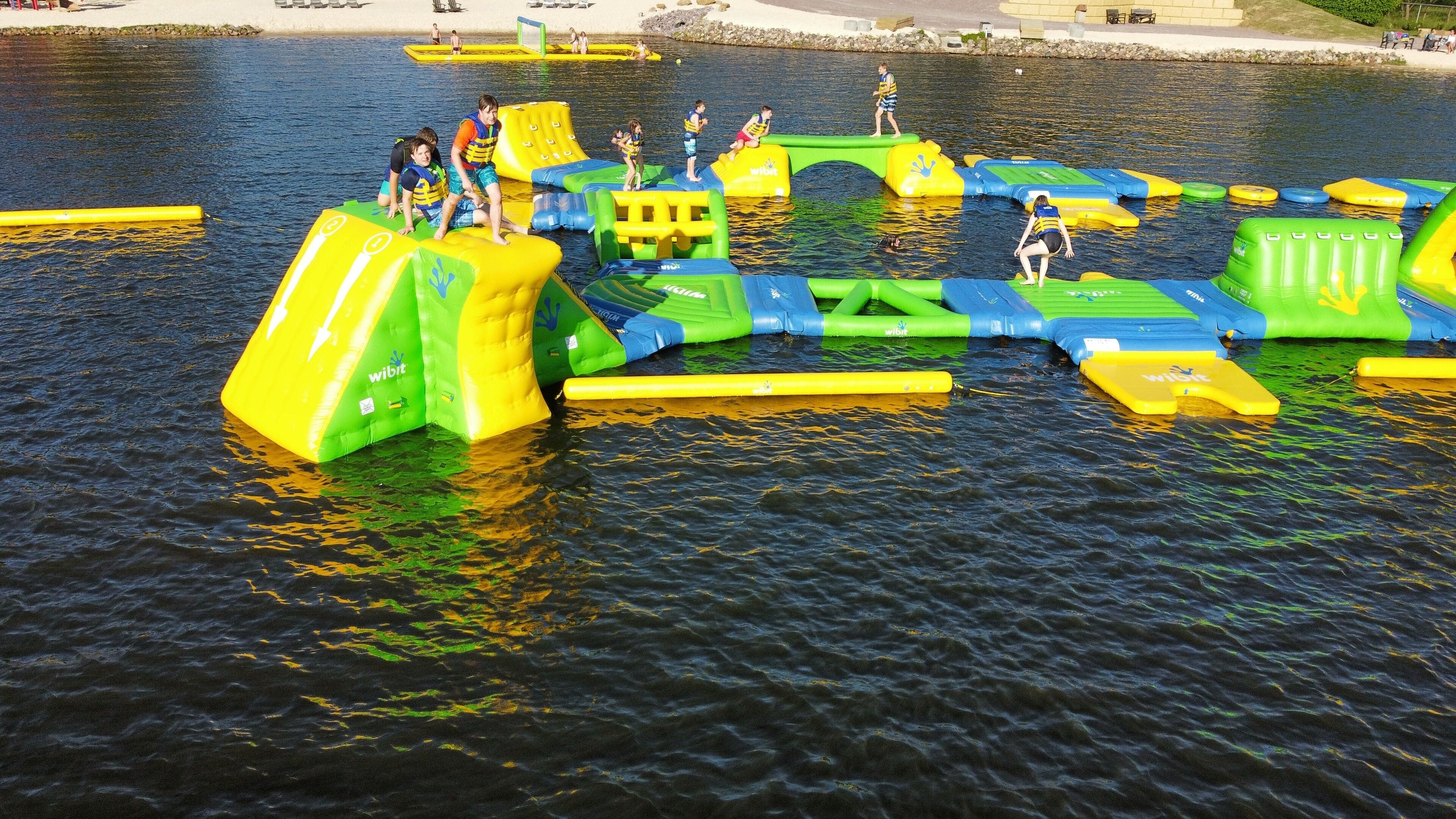 Ein Wasserpark mit Hüpfburgen und einem Strandabschnitt.