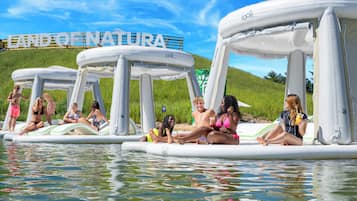 Estructuras inflables con gente relajándose, un cartel que dice "LAND OF NATURE" y una colina cubierta de hierba al fondo.