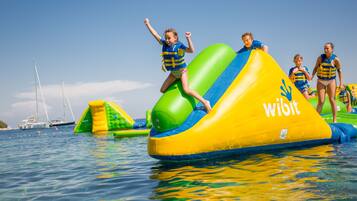 A water activity area with inflatable structures and people participating in water sports.