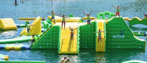 An outdoor water park with inflatable play structures and a sandy beach area.