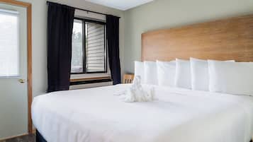 A hotel room with a large bed, a wooden headboard, and a window with curtains.