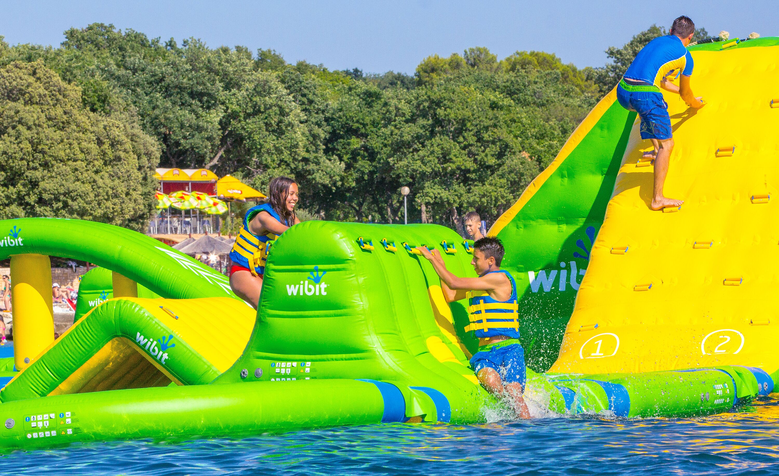Inflatable water slides and pools with people using them.