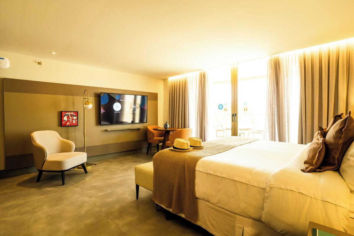 Une chambre d’hôtel avec un grand lit, un téléviseur fixé au mur, un bureau et une chaise.