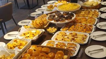 Una mesa de buffet con distintos alimentos y una planta en maceta.