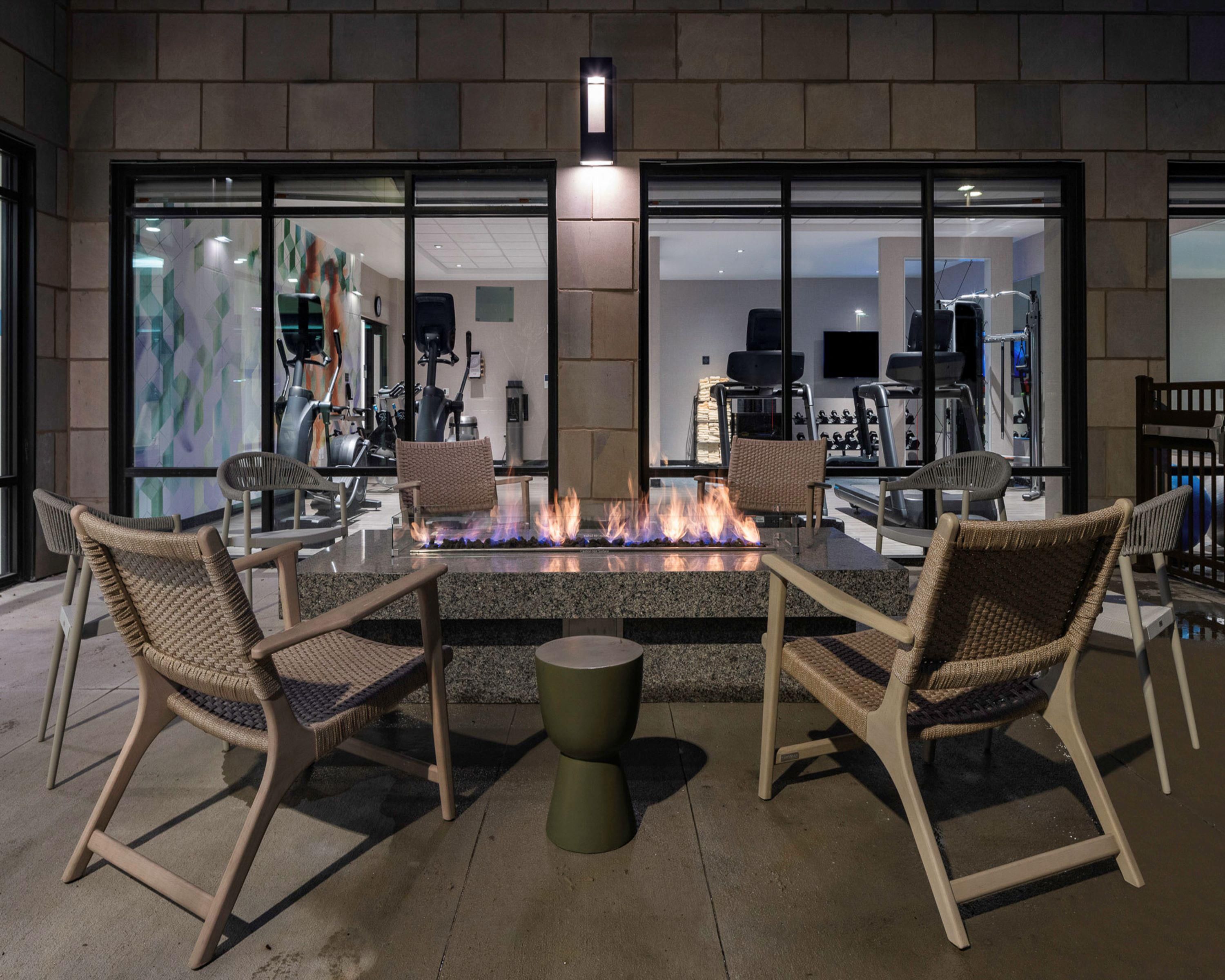 An outdoor seating area with a fire feature, chairs, and a table.