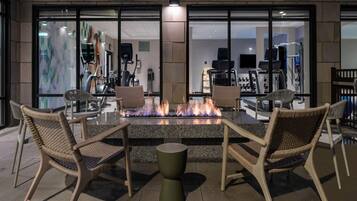 An outdoor seating area with a fire feature, chairs, and a table.