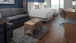 Een moderne hotelkamer met een groot bed, een bank, een bureau en uitzicht op de stad.