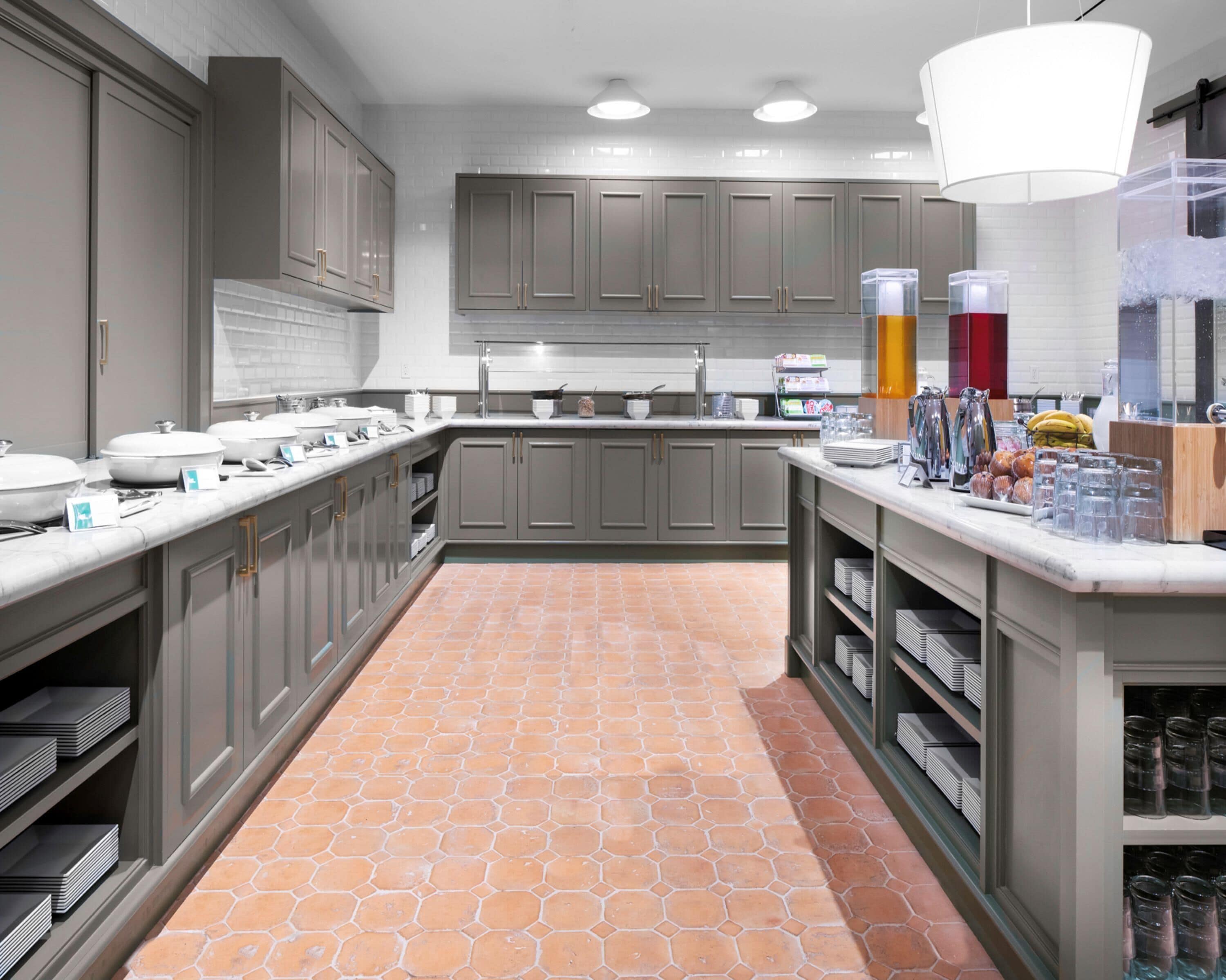 A modern kitchen with grey cabinets, a tiled floor, and a countertop with various items.