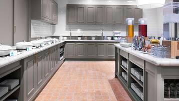 A modern kitchen with grey cabinets, a tiled floor, and a countertop with various items.