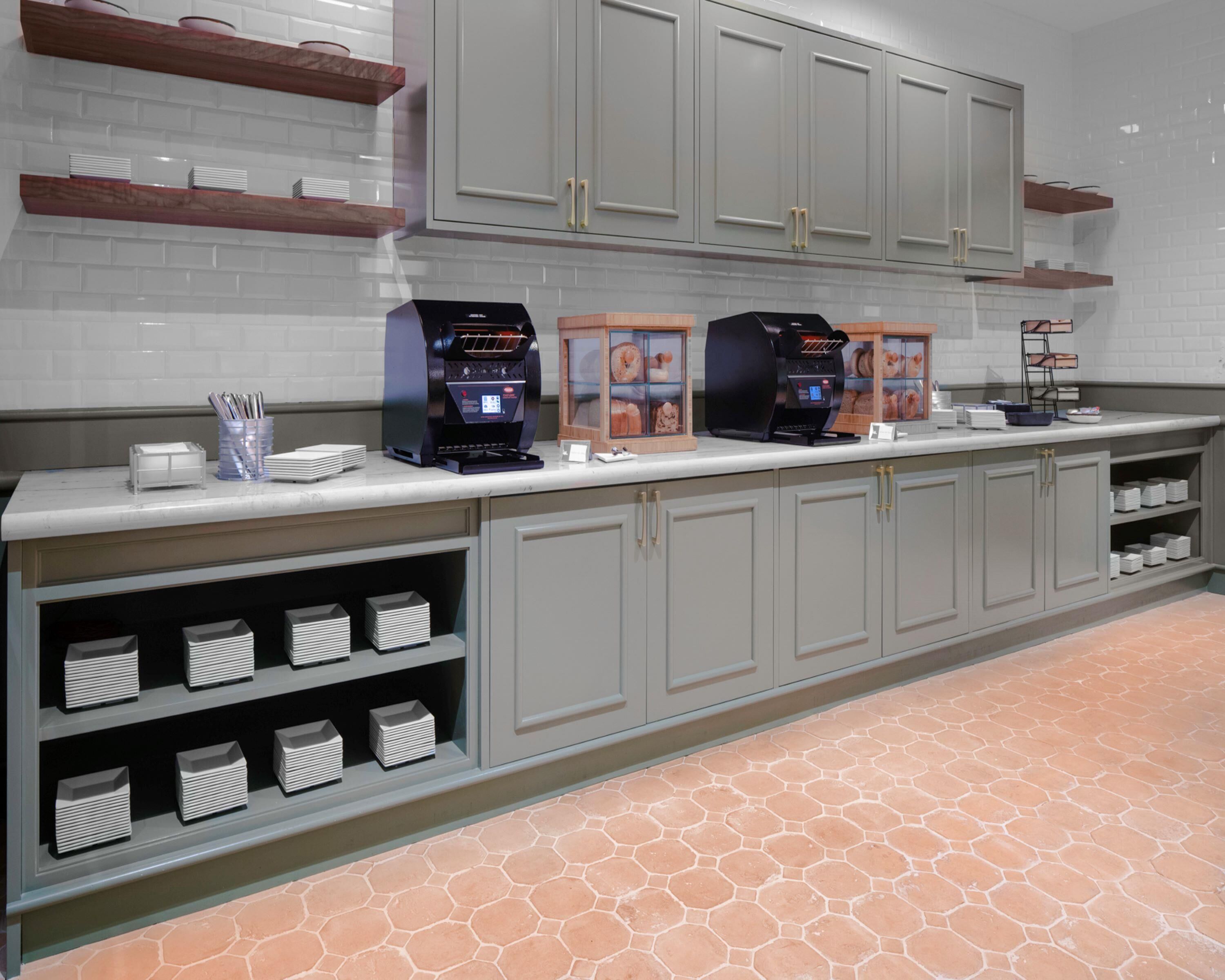 A modern kitchen with grey cabinets, a marble countertop, and a hexagonal tile floor.