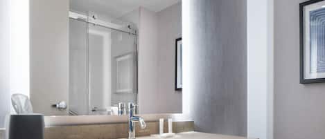 A modern bathroom with a large mirror, a sink, and a towel rack.