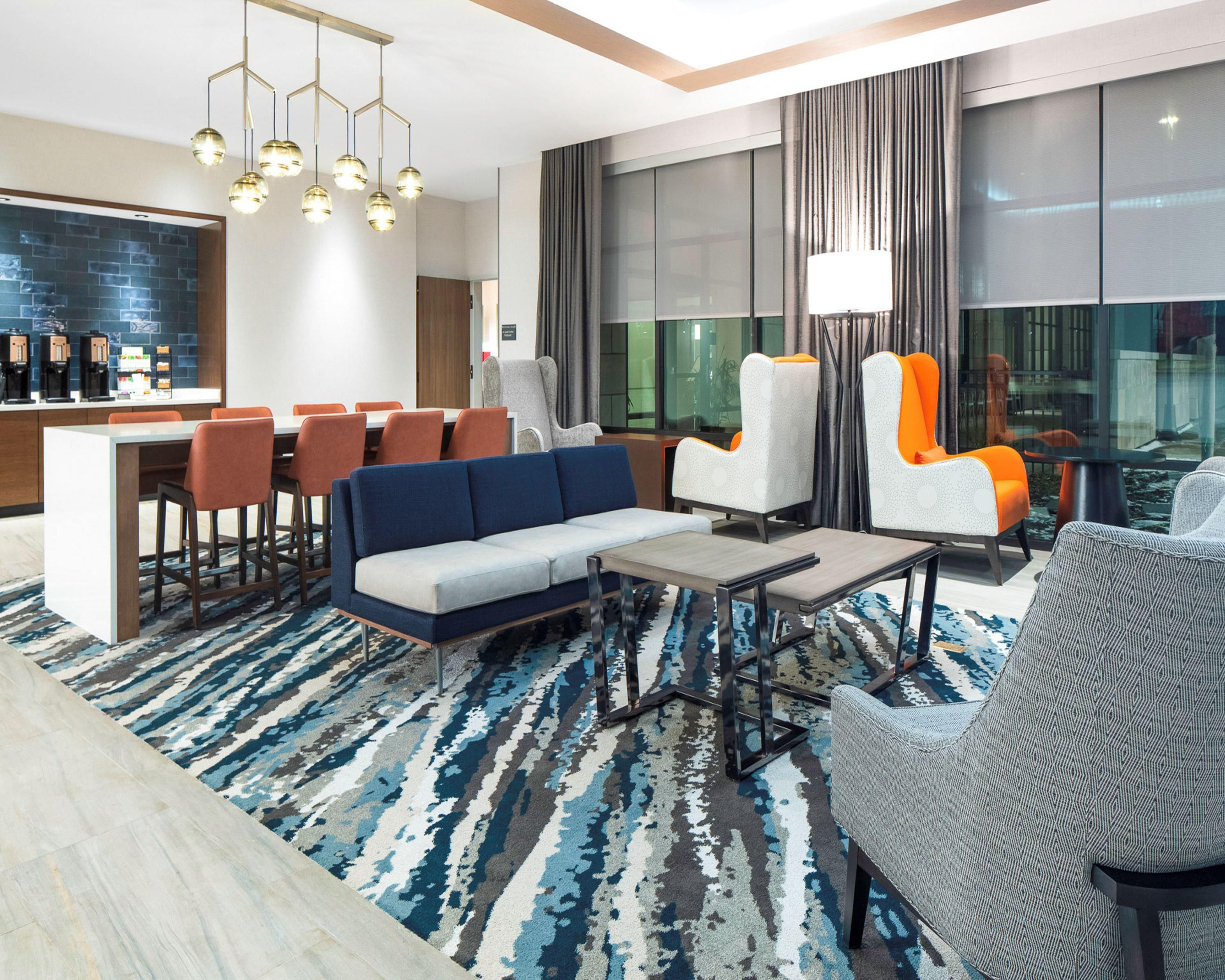 A modern hotel lobby with a bar, seating area, and large windows.