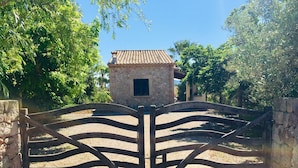 A gated entrance with a stone wall and a tiled-roof building in the background. - Lovely villa in Pollença, countryside (pollença)