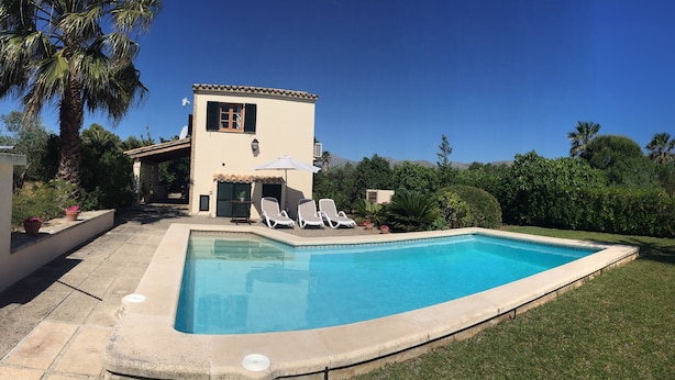 A swimming pool with a tiled deck, a small building with a window and shutter, and a few lounge chairs. - Lovely villa in Pollença, countryside (pollença)