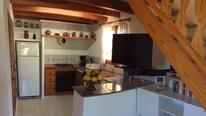 A kitchen with a refrigerator, stove, and a fruit bowl on the counter. - Lovely villa in Pollença, countryside (pollença)