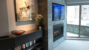 Un salon moderne avec une cheminée, un téléviseur fixé au mur et un tableau représentant un cerf.