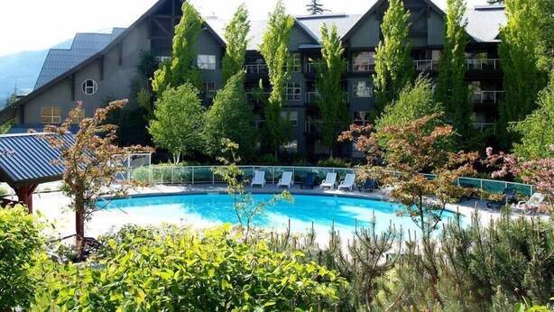 Un hôtel doté d’une piscine entourée de chaises longues et de verdure.
