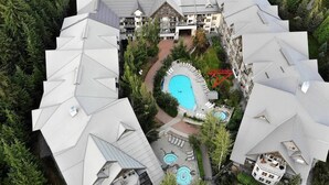 Un hôtel à plusieurs étages doté d’une cour intérieure où se trouve une piscine, le tout entouré d’une végétation luxuriante et agrémenté de nombreux balcons.