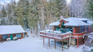 A cabin with a wooden exterior, a balcony, and a snow-covered roof.