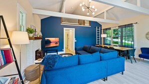 A modern living room with a blue sofa, a dining table, and a TV.