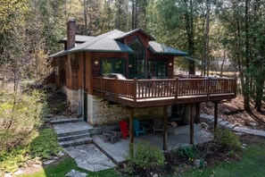 Una cabaña de troncos con terraza, asientos exteriores y cimientos de piedra.