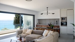 Un salón moderno con un sofá grande, una mesa de comedor y una cocina con vistas al mar.