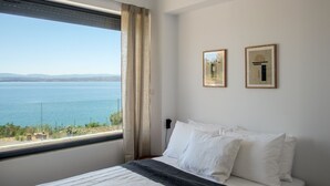 Un dormitorio con un ventanal que ofrece vistas al mar. Hay dos cuadros en la pared.
