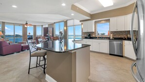 Una cocina amplia con una isla grande, armarios blancos y vistas al exterior.