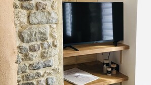 Ett rum med en vägg av sten, hyllor i trä, en platt-TV och en tidning på hyllan.