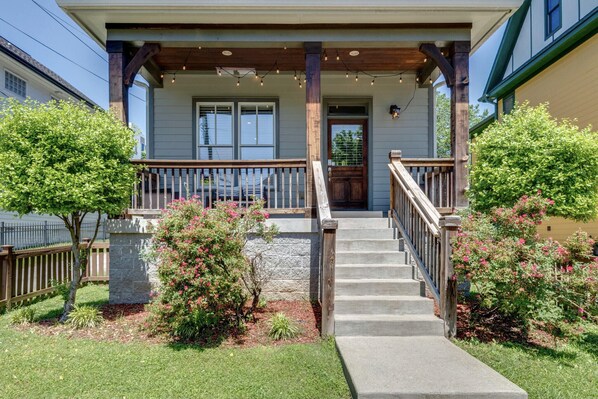 Step up to the charming front porch, adorned with string lights, and enter through the stone-framed front door.