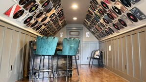 Un couloir dont un mur est recouvert de disques vinyle et d’affiches, qui mène à un espace détente avec des fauteuils turquoise et un plancher en bois.