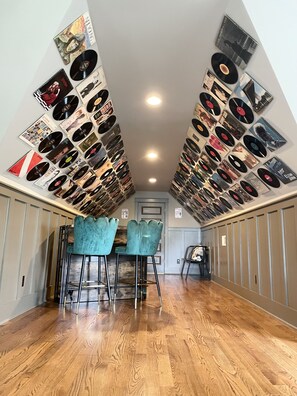Experience the unique ceiling design featuring a triangular pattern of vinyl records in this stylish room.