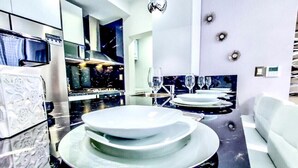 Una cocina moderna con una isla central, electrodomésticos integrados y un comedor con sofá y platos decorativos.