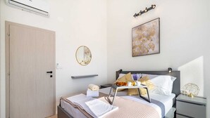 A modern bedroom with a bed, bedside table, nightstand, and a wall-mounted air conditioner.