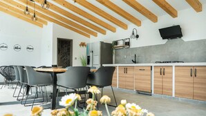 A modern kitchen with wooden beams, a dining area with black chairs, and a TV mounted on the wall.