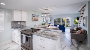 A modern kitchen with a built-in stove, white cabinetry, and a marble countertop.