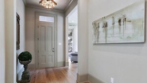 Un corridoio con pavimento in legno, una porta bianca e un quadro appeso al muro.