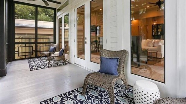 Un ampio balcone con ventilatore a soffitto, tappeto decorato e mobili in vimini.