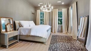 Camera da letto con un letto, un comodino, uno specchio, un lampadario e un tappeto decorato.