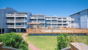 Un hotel moderno con varios balcones, un área de piscina y un césped bien cuidado.