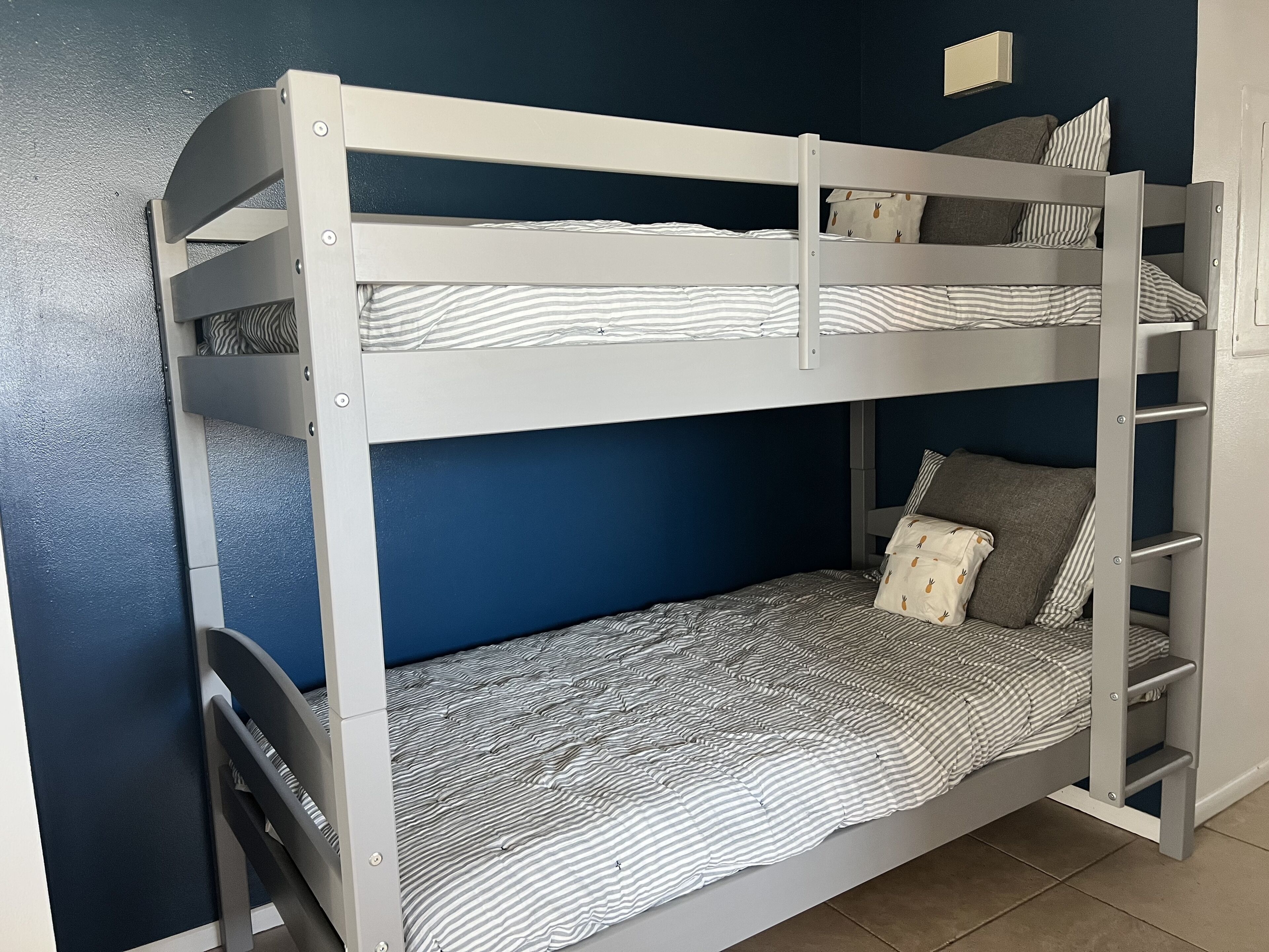 A bunk bed with two levels, each with a striped mattress and pillows.