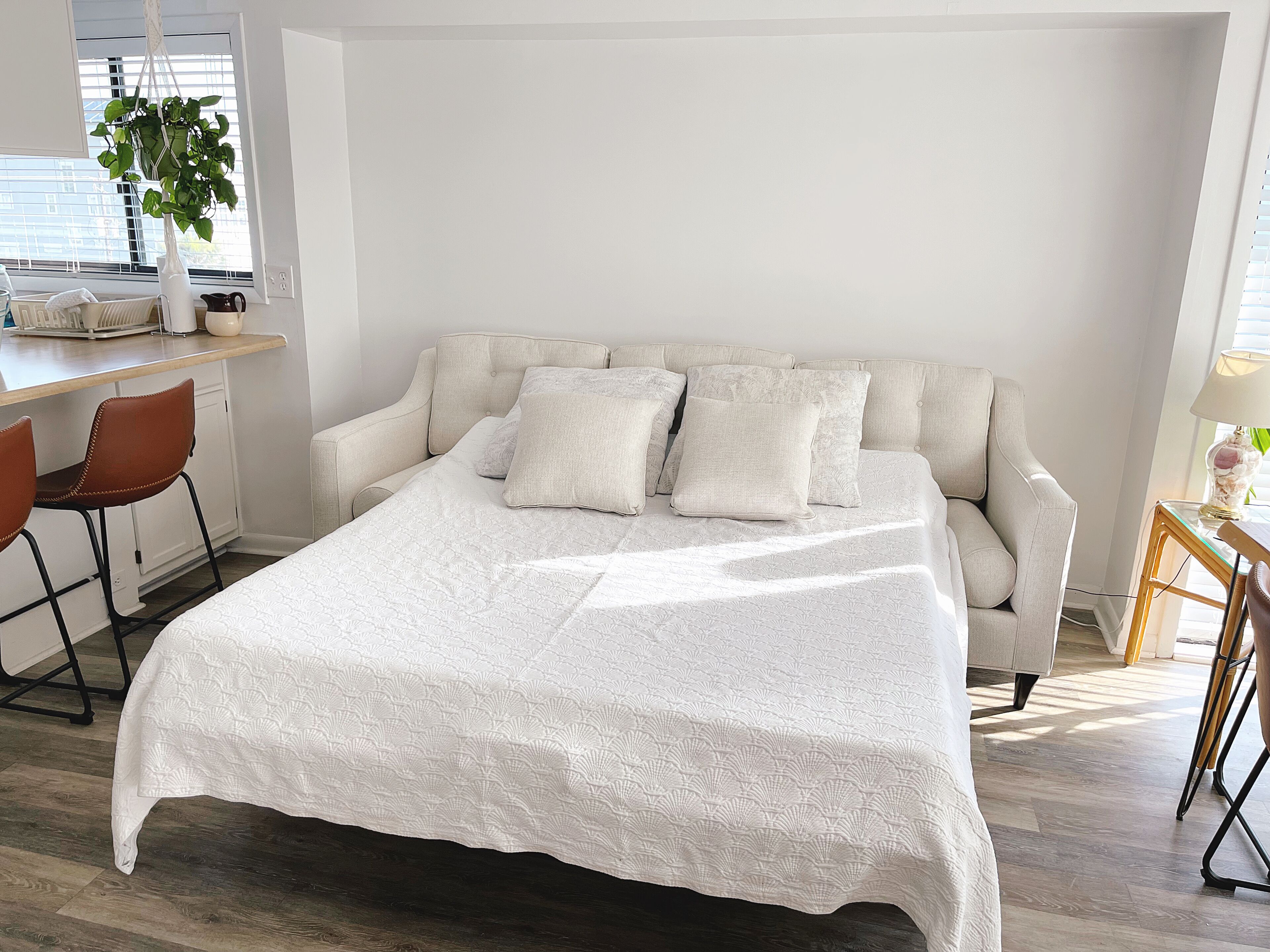 Quarto com cama, escrivaninha, cadeira e planta em vaso.