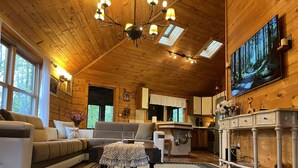 A cozy cabin interior with a wooden ceiling, a sofa, a coffee table, a fireplace, and a kitchen area. - Perfect getaway from your daily routine!!! (Greentown)