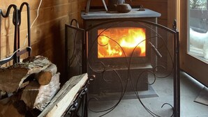 A cozy cabin interior with a wood-burning stove, a fireplace, and a window with a view of the outdoors. - Perfect getaway from your daily routine!!! (Greentown)