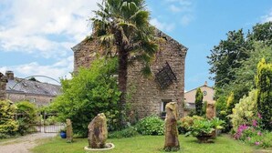 A stone building with a garden, including a palm tree and large rocks. - Keriker - PLOEMEL - Gîte (PLOEMEL)