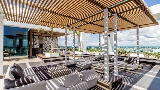 Un salón en la azotea con asientos al aire libre, una pérgola y vistas a la ciudad.