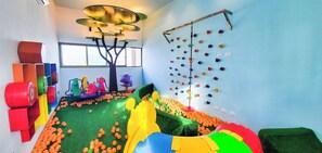 A play area with a ball pit, climbing wall, and colorful play structures.